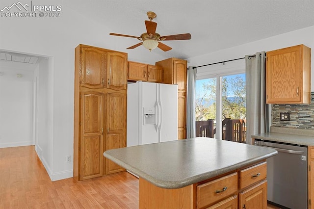 3925 Zurich Dr, Colorado Springs, CO 80920 - kitchen featuring stainless steel dishwasher, white refrigerator with ice dispenser, ceiling fan, light wood-style flooring, and backsplash