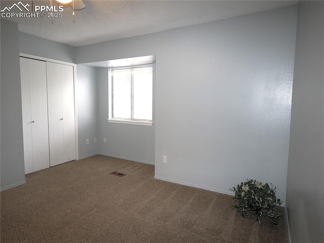 unfurnished bedroom with carpet flooring, a closet, visible vents, baseboards, and a textured ceiling