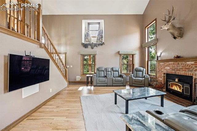 living area with stairs, wood finished floors, a fireplace, baseboards, and a high ceiling