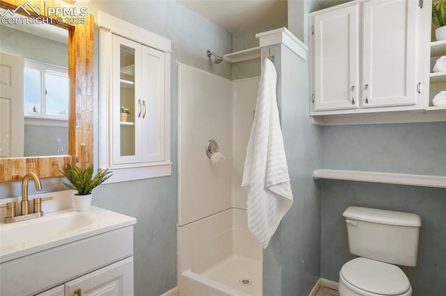 bathroom with vanity, toilet, baseboards, and a stall shower