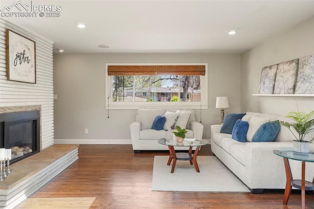 living room with baseboards, recessed lighting, a glass covered fireplace, and wood finished floors
