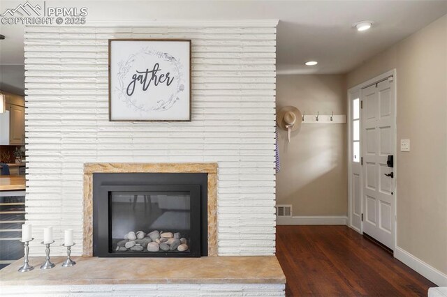 details featuring a large fireplace, recessed lighting, baseboards, wood finished floors, and visible vents