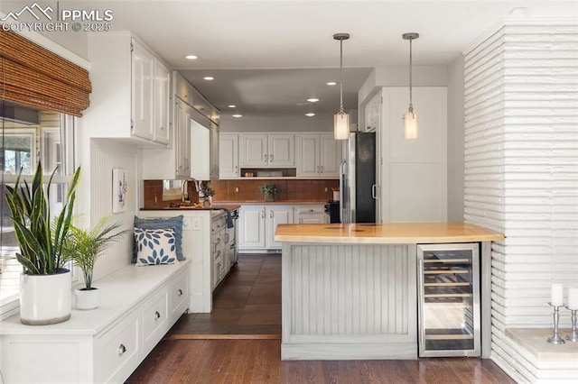 kitchen featuring beverage cooler, freestanding refrigerator, white cabinetry, dark wood-type flooring, and pendant lighting