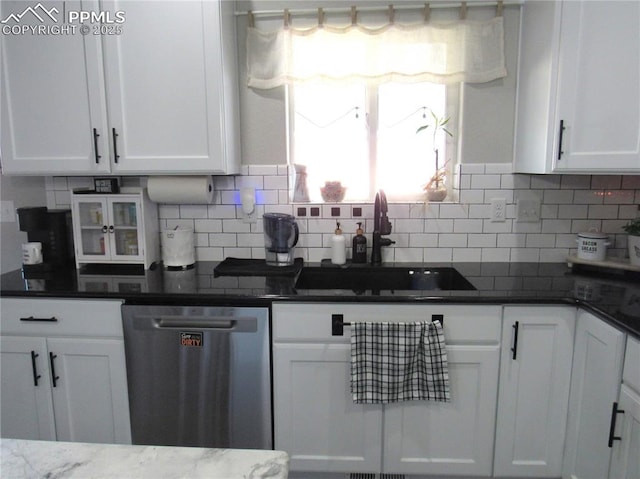 8766 Beaverhead Cir, Colorado Springs, CO 80908 - kitchen with stainless steel dishwasher, a sink, white cabinets, decorative backsplash, and dark stone countertops