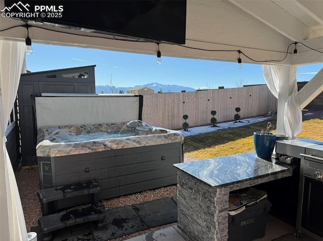 8766 Beaverhead Cir, Colorado Springs, CO 80908 - view of patio / terrace with a hot tub, a fenced backyard, a mountain view, and exterior kitchen