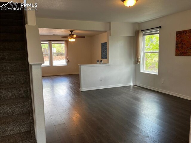2790 Winterbourne St, Colorado Springs, CO 80910 - unfurnished living room featuring stairway, plenty of natural light, baseboards, and dark wood finished floors