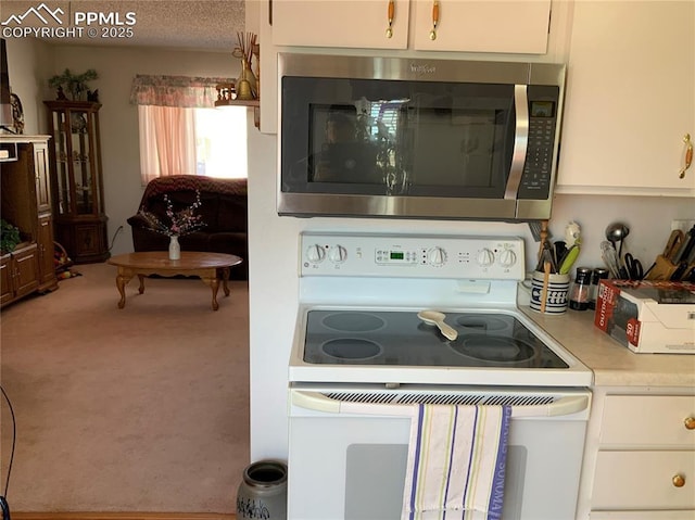 6905 Chippewa Rd, Colorado Springs, CO 80915 - kitchen featuring stainless steel microwave, electric range, carpet, light countertops, and white cabinetry