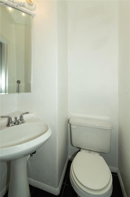 bathroom with baseboards, tile patterned floors, and toilet