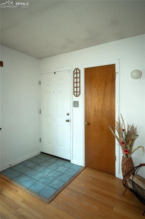 entryway featuring baseboards, a textured ceiling, and wood finished floors