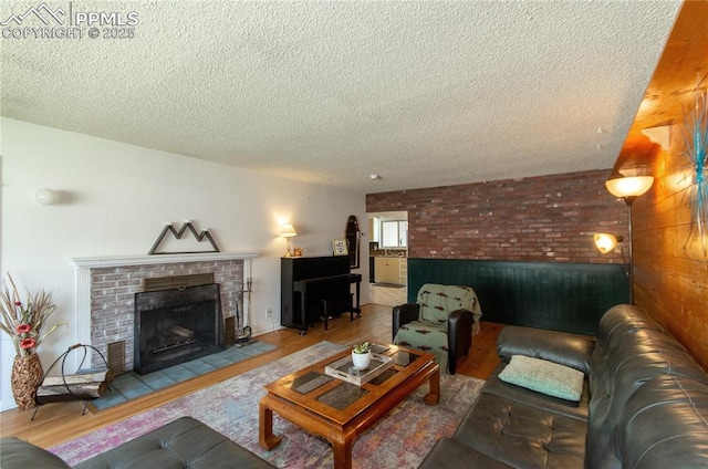 living area featuring a textured ceiling, wood finished floors, and a fireplace