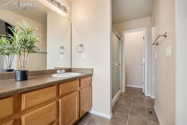 bathroom with a stall shower, tile patterned floors, baseboards, and vanity