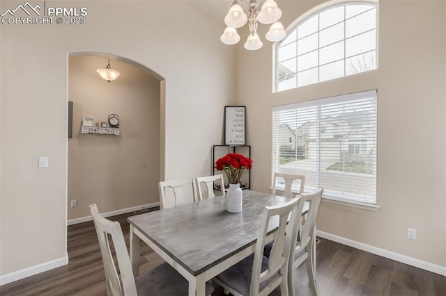 dining space featuring baseboards, arched walkways, wood finished floors, and a healthy amount of sunlight