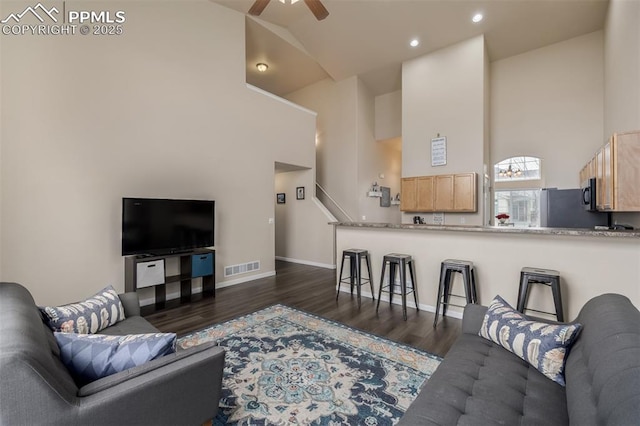 living room featuring visible vents, baseboards, dark wood-style floors, high vaulted ceiling, and a ceiling fan