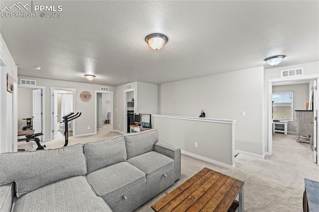 living area featuring visible vents, a textured ceiling, and light carpet