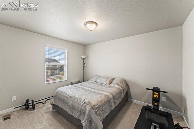 bedroom featuring a textured ceiling, baseboards, visible vents, and carpet