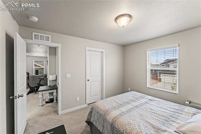 bedroom with visible vents, a textured ceiling, baseboards, and light colored carpet