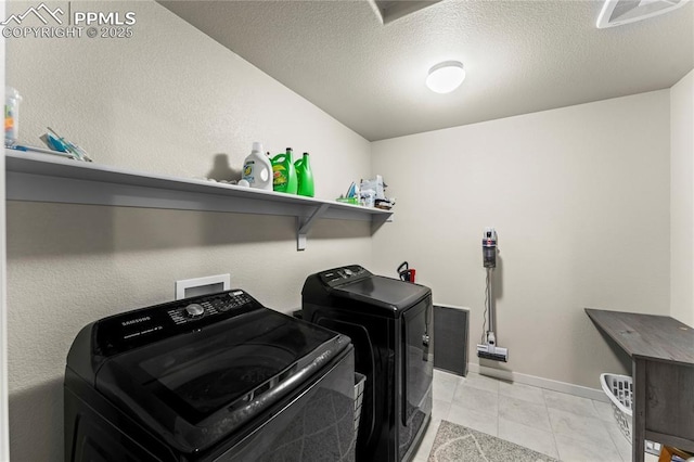 washroom featuring laundry area, visible vents, washing machine and dryer, baseboards, and light tile patterned floors