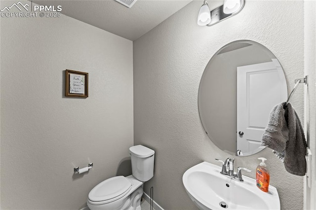 bathroom with toilet, baseboards, and a sink
