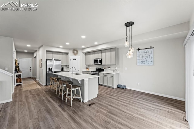 kitchen with gray cabinetry, appliances with stainless steel finishes, a breakfast bar, and recessed lighting