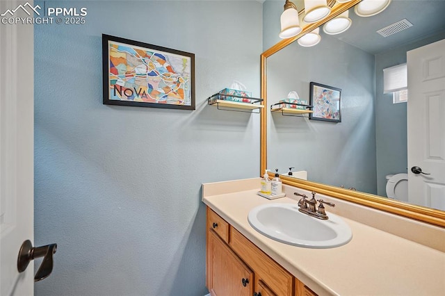 bathroom featuring toilet, visible vents, and vanity