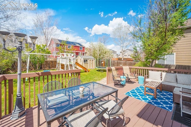 wooden terrace with a trampoline, a storage shed, an outdoor hangout area, a playground, and outdoor dining space