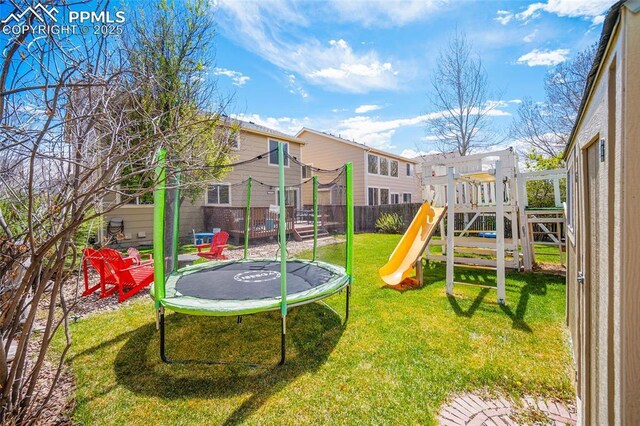 view of playground featuring fence, a trampoline, and a lawn