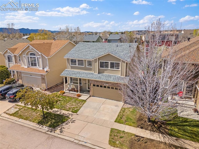 traditional-style home with a porch, an attached garage, driveway, and a residential view