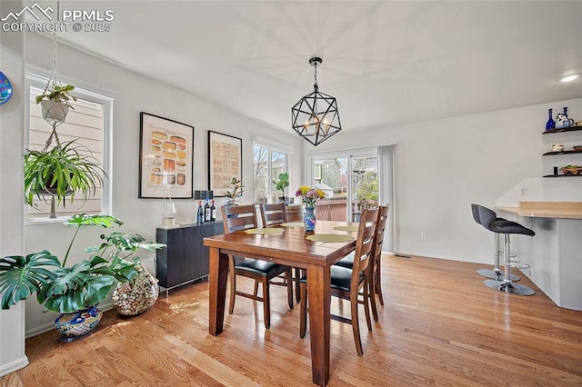 dining room featuring baseboards, light wood finished floors, and a chandelier