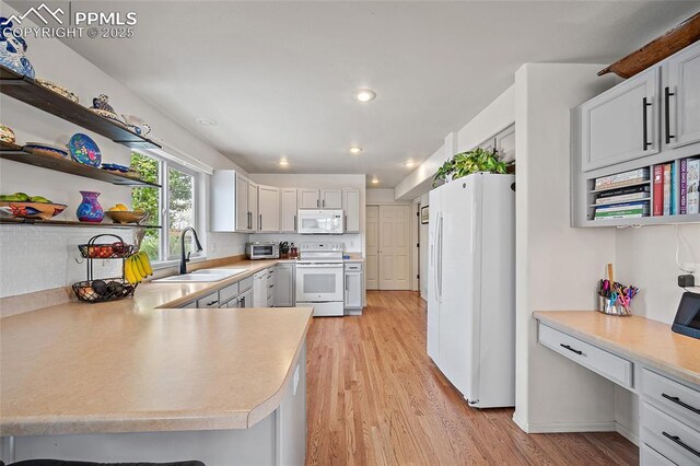 kitchen with light wood-style floors, a sink, white appliances, and light countertops