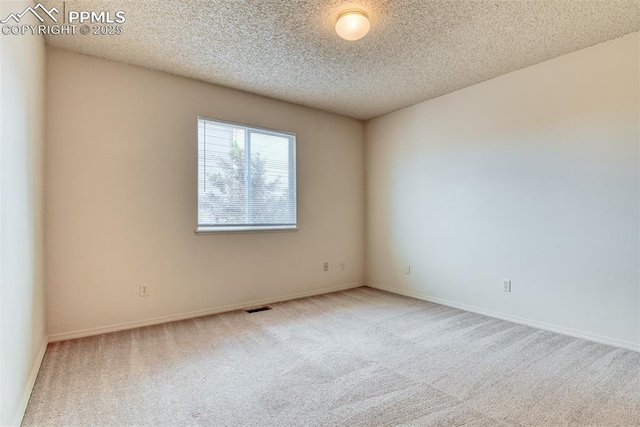 carpeted spare room featuring baseboards, a textured ceiling, and visible vents