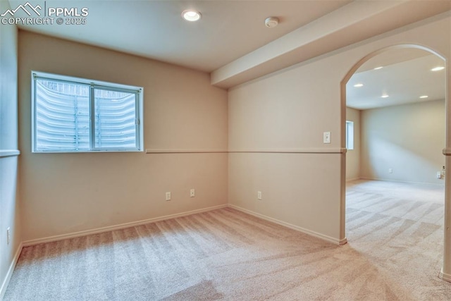 unfurnished room with baseboards, arched walkways, carpet, and a healthy amount of sunlight