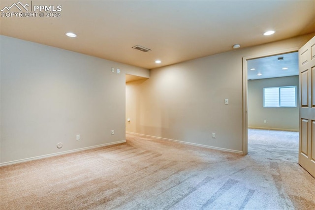 empty room featuring light colored carpet, recessed lighting, and baseboards