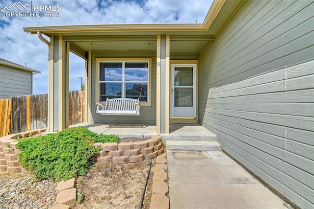 doorway to property with fence and covered porch