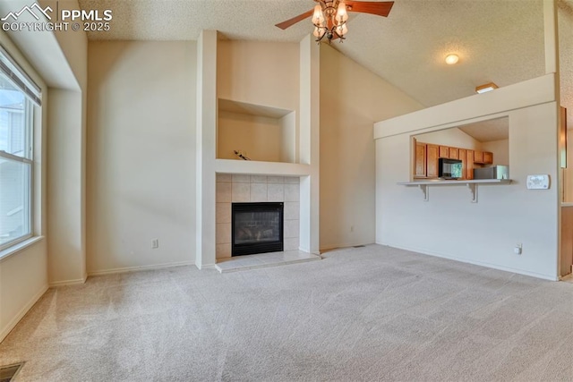 unfurnished living room featuring a ceiling fan, a textured ceiling, a wealth of natural light, and light carpet