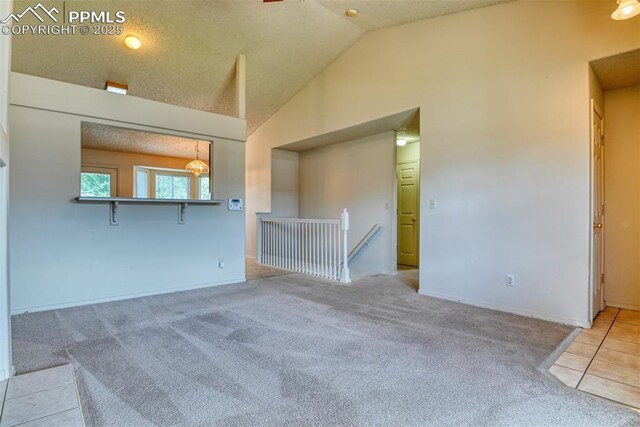 carpeted spare room featuring baseboards and high vaulted ceiling