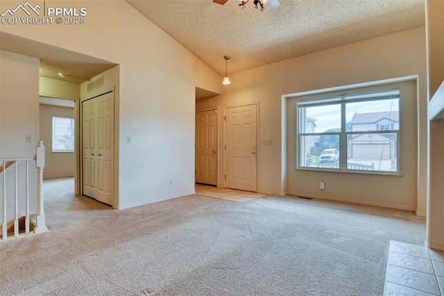 spare room featuring light carpet, a textured ceiling, and visible vents