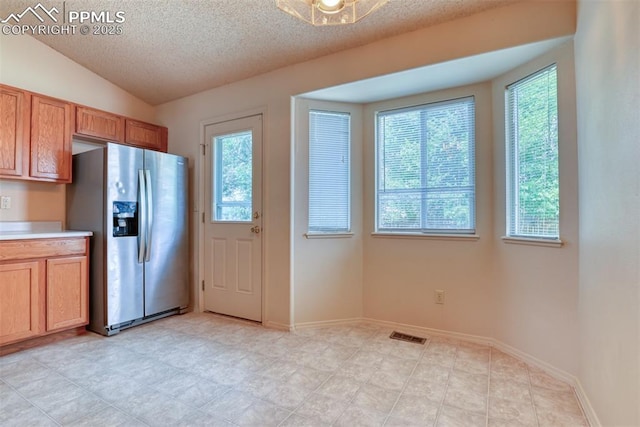 kitchen with light countertops, stainless steel fridge with ice dispenser, a textured ceiling, and a wealth of natural light