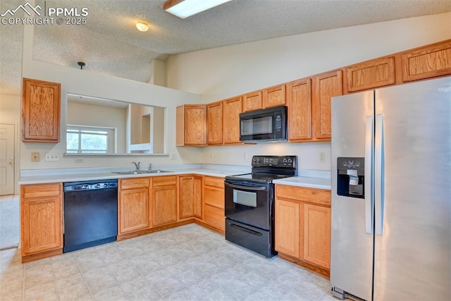 kitchen with a textured ceiling, vaulted ceiling, light countertops, a sink, and black appliances