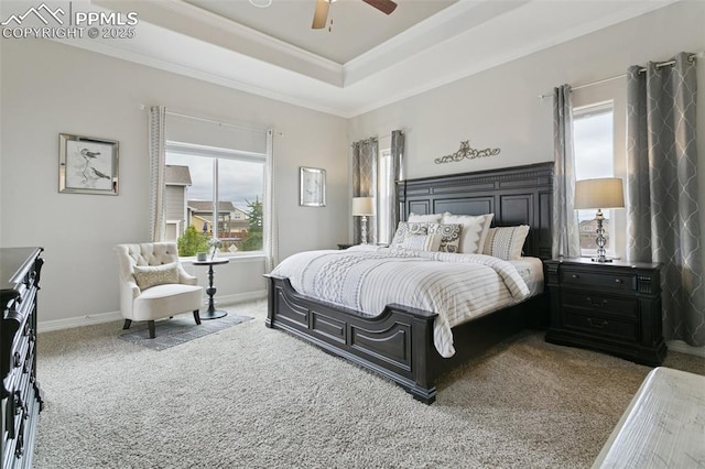 bedroom with carpet floors, a tray ceiling, and multiple windows