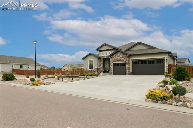 craftsman-style home with a garage, fence, concrete driveway, and stone siding