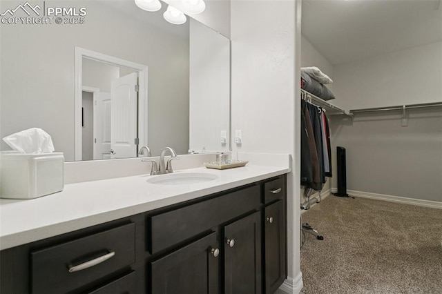 bathroom featuring vanity, baseboards, and a walk in closet