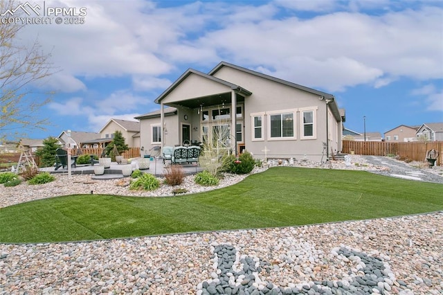 rear view of property featuring fence, a patio, stucco siding, an outdoor hangout area, and a yard