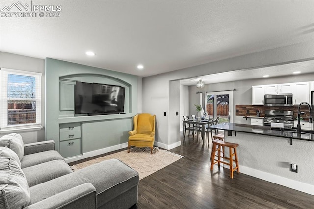 living room with baseboards, dark wood-style flooring, recessed lighting, and a wealth of natural light