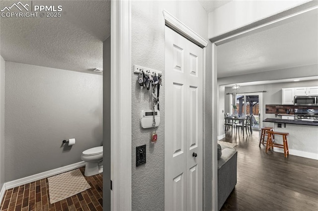 bathroom with baseboards, a textured ceiling, and toilet