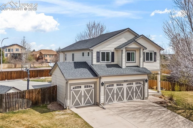 garage featuring fence, concrete driveway, and a residential view