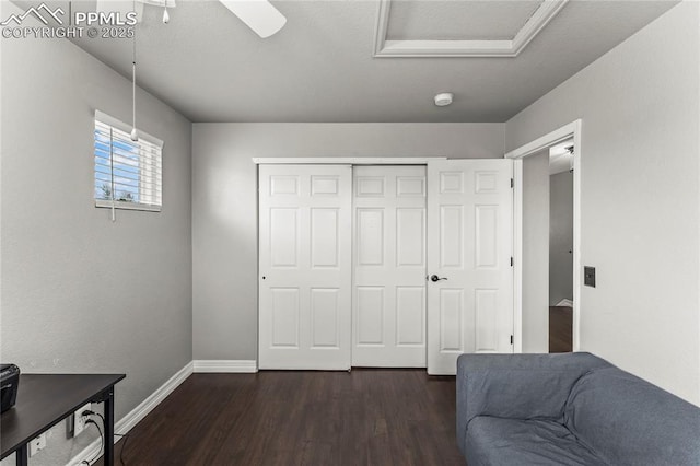 living area featuring baseboards, attic access, and dark wood-type flooring