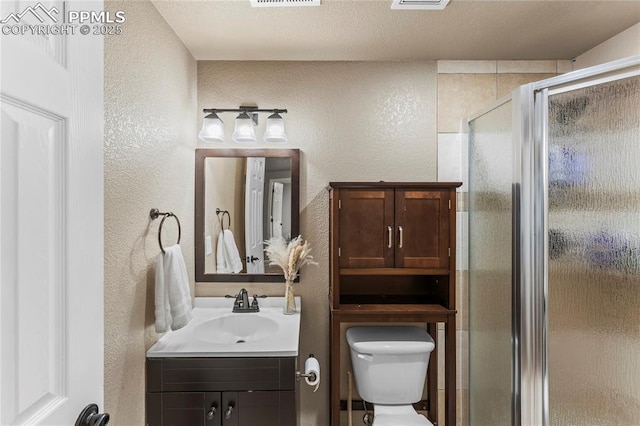 bathroom with toilet, a textured wall, and a stall shower