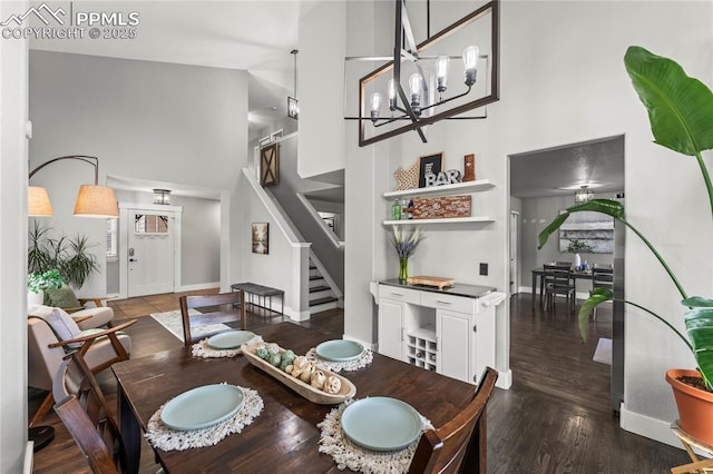 dining space featuring wood finished floors, baseboards, stairs, and a high ceiling