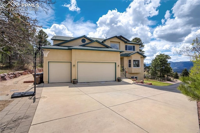 traditional-style house featuring stucco siding, driveway, and an attached garage