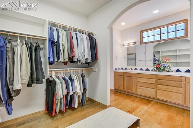 spacious closet featuring arched walkways and light wood finished floors